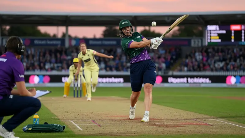 Women's cricket batter striking through the off side during a day-night limited-overs innings